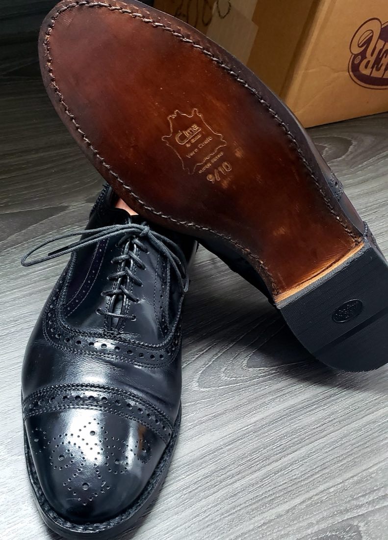 A black cap-toe oxford beside its freshly stitched new leather sole